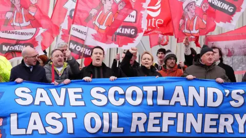 Pennsylvania media unionists behind blue banner holding placards reading the last refinery of Save Scotland