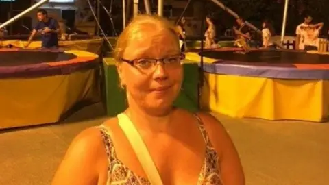 GMP/Family handout Emma McGowan has tied back blnde hair, spectacles and wears a sleevelesss dress. She is at a fun fair.