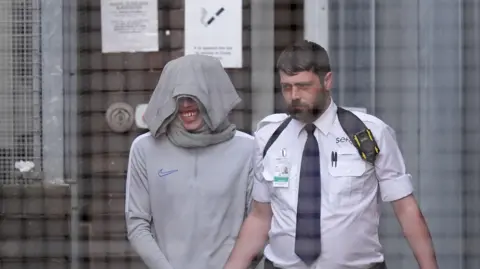 PA Media A man is being led out of court by a prison officer. 