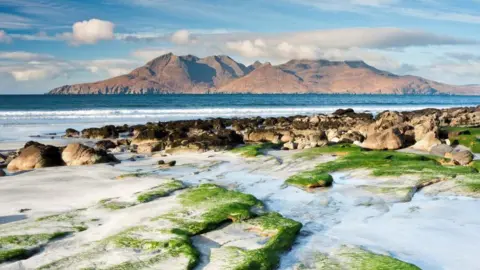 Getty Images The Isle of Rum in sunshine and pictured from a rocky beach