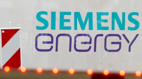 Getty Images An image of the Siemens Energy logo. The word Siemens is in light blue and the word energy is in purple. There's a red and white pattern to the side of the logo.