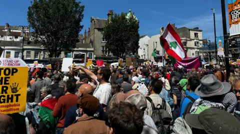 A group of people holding up anti-racism signs and various other flags.