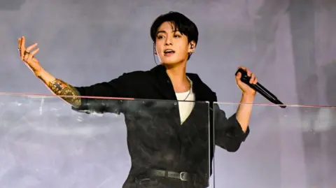 Getty Images BTS vocalist Jungkook, in a black long-sleeved shirt, midway through a performance on stage