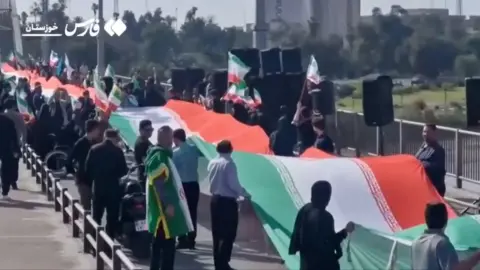 People holding large Iranian flag form human chain on bridge 