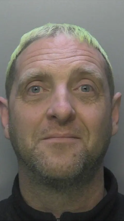 Police custody shot of a man with died blonde hair and stubble