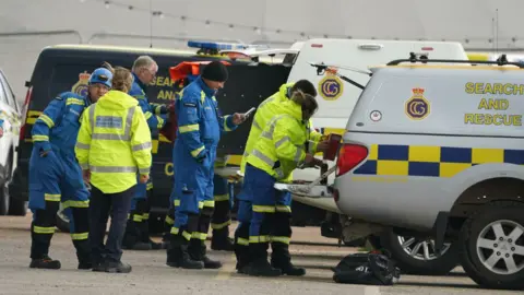 PA Media Half a dozen coastguard crews working in the back of search and rescue vehicles