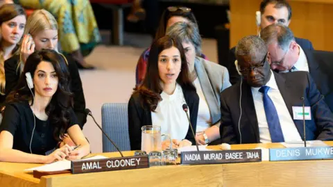 Getty Images Nadia Murad (C) addresses a UN Security Council meeting in New York, alongside Amal Clooney (L) and Denis Mukwege (R) (23 April 2019)