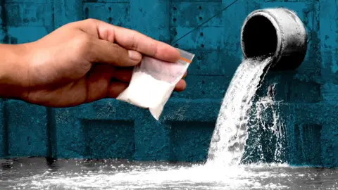 A composite graphic which shows a close-up of a hand holding a small bag of white powder - drugs - overlaid on a sewage pipe out of which a steady stream of water is emerging