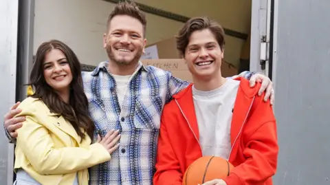 Lime Pictures Matthew Wolfenden, Rebecca Ryan and Lewis Walton are all laughing as they stand in front of a removal van. 