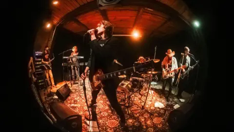 Yuri Gryaznov A fish-eye lens captures a band performing on a makeshift stage with guitars