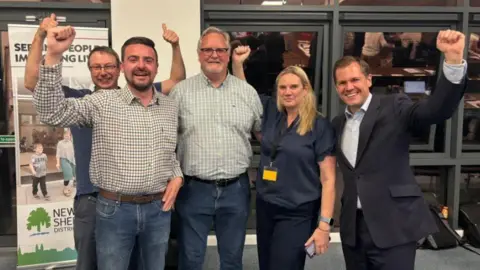 Five people celebrating a by-election win. Robert Jenrick is on the far-right of the picture.