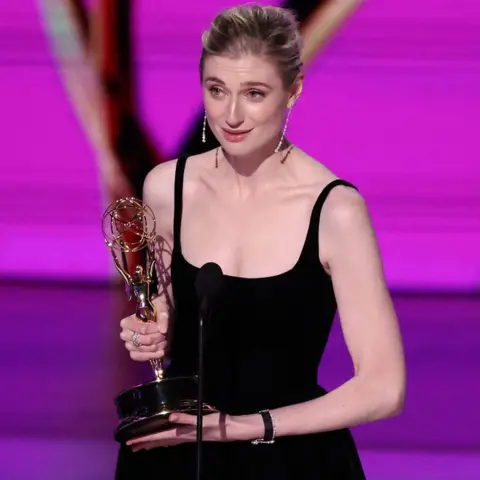 Elizabeth Debicki of Reuters holding her Emmy on stage