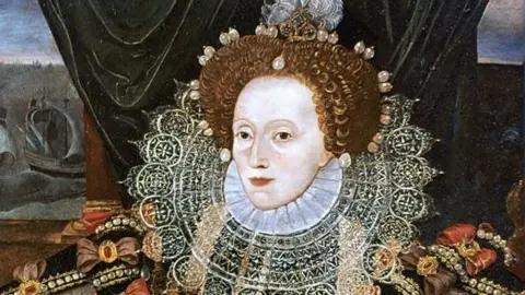 Getty Images A detailed portrait shows Queen Elizabeth I in an elaborate embroidered gown with pearl jewellery, a lace ruff collar and a jewelled hairstyle, seated indoors with heavy draped curtains and ships visible through a window in the background.
