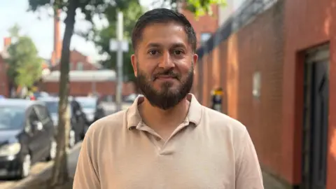 Kashif Akram. He has short dark hair and beard, wearing a beige polo shirt.