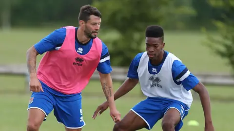 Marc Richards and Ivan Toney in training for Northampton Town in 2014. Richards is in a pink Errea bib and Toney in a white Errea bib