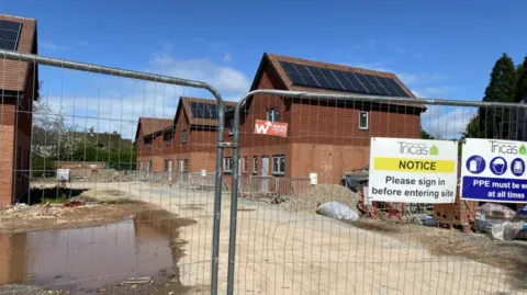 BBC Unfinished homes behind a fence