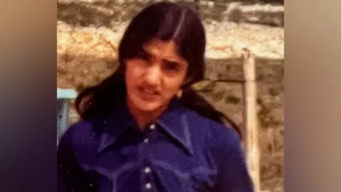 West Midlands Police A woman in a blue-purple shirt outdoors in a vintage photograph.