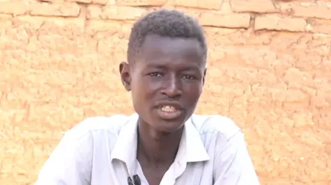 Marwan Mohamed Adam, in a white shirt, is seen talking in Sudan's Tawila town