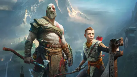 Sony The cover image of 2018's God of War shows main character Kratos wearing leather armour and holding a large axe by his side. His son, Atreus, stands next to him, holding a bow in one hand and using the other to grip the dragon carving on the bow of a Viking rowing boat. A foreboding, snow-covered mountain looms over the pair in the background.