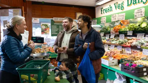 Getty Images Two men and a young boy buying fruit and veg in a greengrocers.