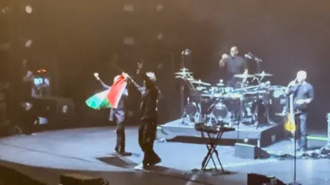 Massive Attack band members holding Palestine flag on stage in Singapore