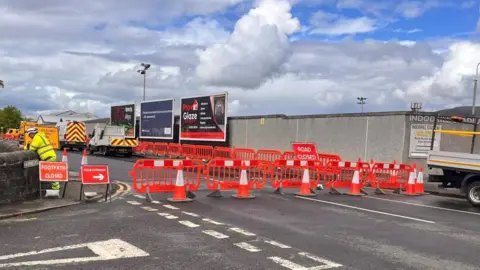 BBC A section of road outside a football stadium. The road is closed with signs indicating this and red barriers placed across the road