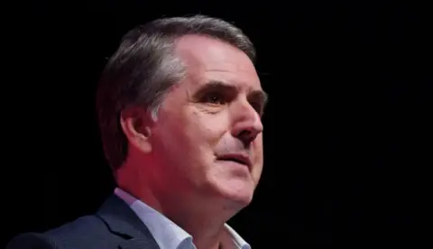 Liverpool City Region Metro Mayor Steve Rotheram, with dark grey hair, wears a pale blue shirt and a dark blue suit jacket.