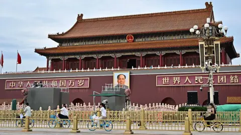 Getty Images People ride past a portrait of the late communist leader Mao Zedong on Tiananmen Square on 28 August.