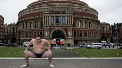 Sumo wrestler wrestler Kitanowaka Daisuke performs a sumo squat outside the Royal Albert Hall.