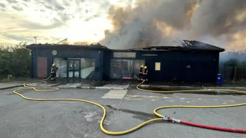 Cambridgeshire Fire and Rescue Service   A burnt former burger king with a fire hose in the foreground 