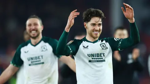 Hayden Hackney (to the forefront on the right) with his arms aloft and a big smile after Middlesbrough's win at Sheffield United with Luke Ayling (behind him in the background on the left) 