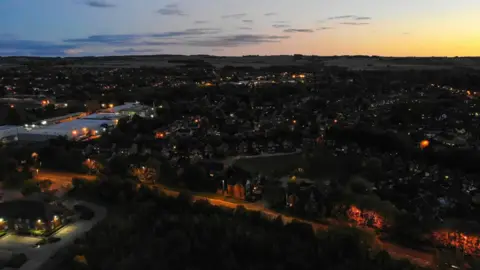 A view over Wantage at dusk, with street lights illuminating paths.