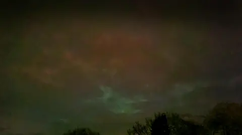 uWhoAndyR/BBC WEATHER WATCHERS Dark moody skies are tinged with green and a brown and pink glow.