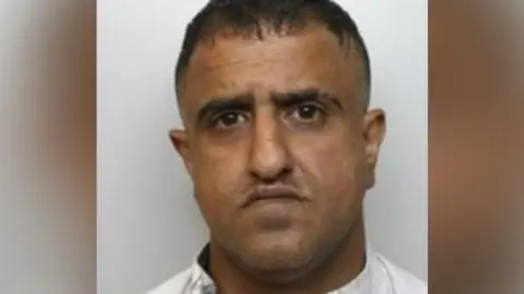 Riyasth Hussain, 45, who is a man wearing a white shirt and who has dark hair. 