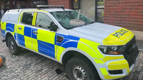 PA Media A police van with a smashed windscreen.