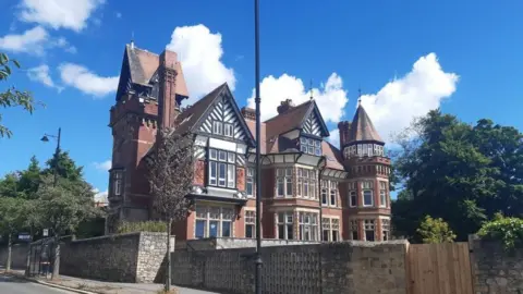 Local Democracy Reporting Service A view of the street, with a bus shelter and Langham Tower behind a stone gate