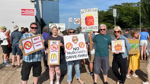 George Carden/BBC Residents standing in the industrial area holding placards which read "not wanted here".