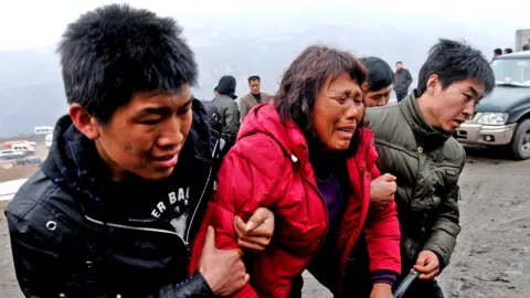 Relatives of trapped coal mine workers are carried away from the site of a flooding accident at the coal mine, sitting astride Xiangning County of Linfen City and Hejin City of Yuncheng City, Shanxi province March 29, 2010. 