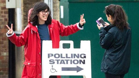 Two young women pose in front of a Polling Station sign during the UK General Election in June 2017