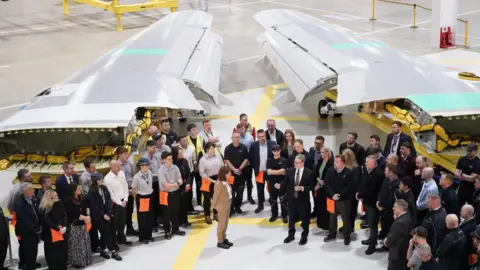 Getty Images First Minister Eluned Morgan and Prime Minister Sir Kier Starmer stand in front of staff at a factory. Two large airplane wings are behind the group.