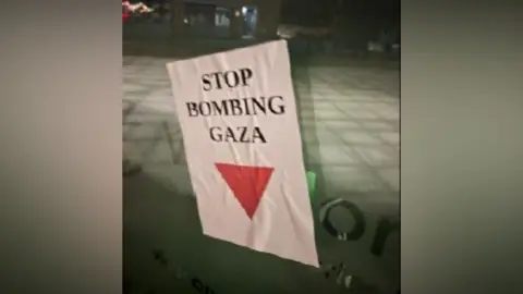 Eastern Region Special Operations Unit A poster reading "stop bombing Gaza" with a red triangle drawn on it can be seen attached to a window. 