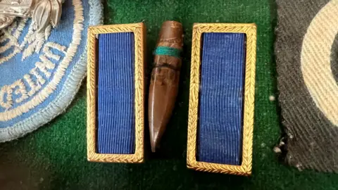 A close up image showing a brown bullet resting between two blue embroidered tags. 