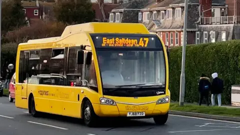 a yellow bus with East Saltdean 47 written on a digital board at the front passes along a road