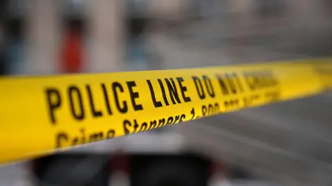 A yellow strip of police tape reads "Police line do not cross".