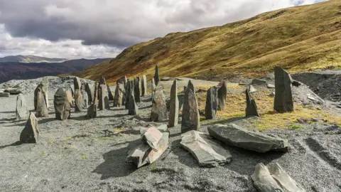 Large blocks of slate from the mine at Honister Pass. Hills are in the background, set against a gloomy, cloudy sky.