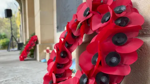 A poppy wreath is propped up against a wall at Arnos Vale cemetary for Armistice Day. 