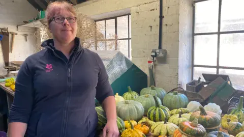 Barrington Court's senior gardener Jemma Marsh standing in one of the shed's at the National Trust property.  In the background is some of this year's pumpkin and squash harvest.