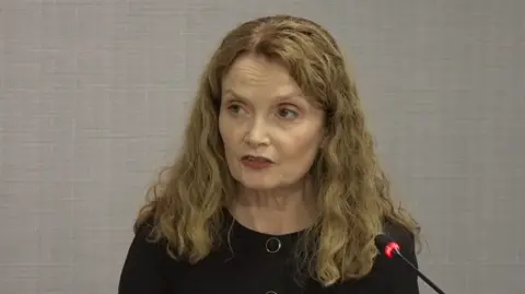 Eljamel Inquiry Una Doherty KC, a woman with shoulder-length blonde hair and a black top speaks into a microphone