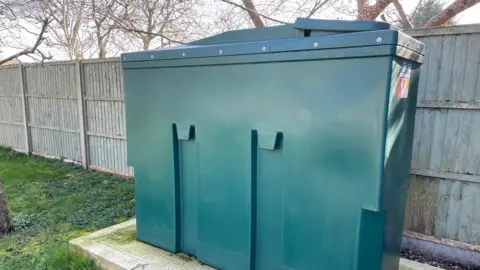 A general green oil tank in a garden. 