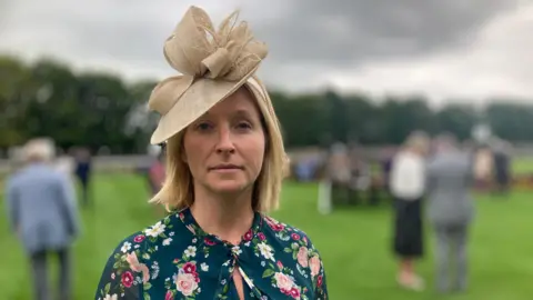 Shaun Whitmore/BBC Sharon Able wearing a floral dress and beige hat